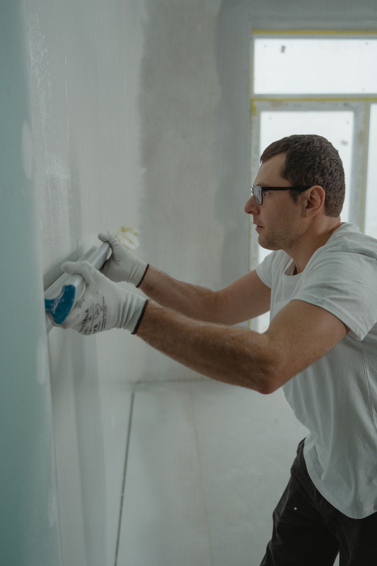 Finisher pressing joint compound into drywall with a taping knife