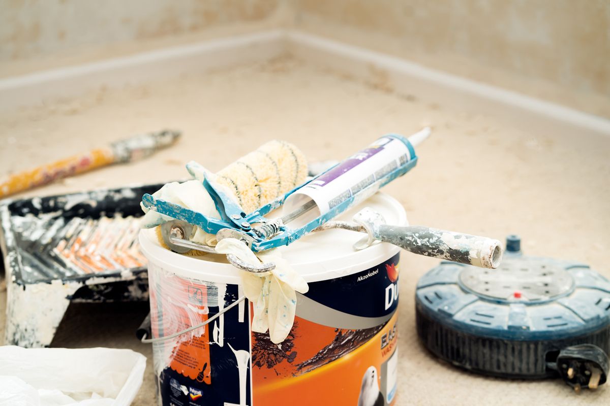 Painting and finishing tools staged on a drop-cloth-protected floor during ceiling work